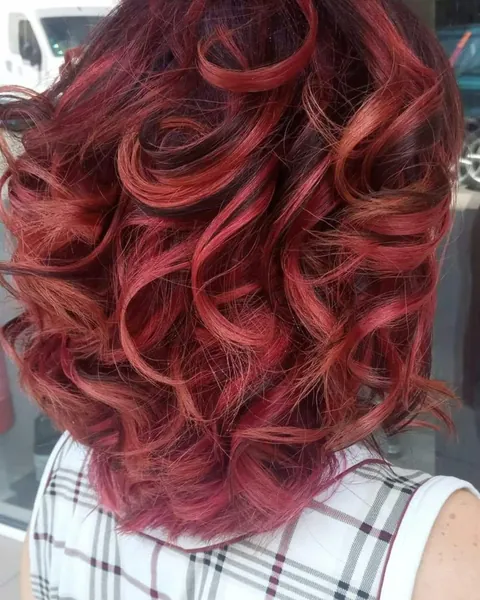 Shoulder-length hair in rich red and copper tones, styled in loose curls